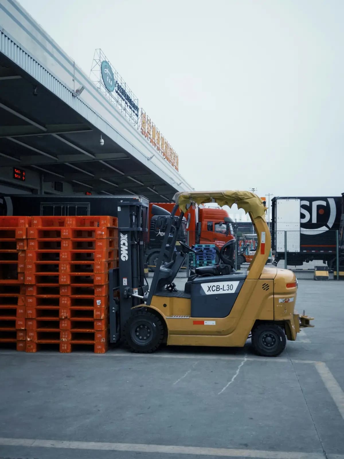 Chariot élévateur garé à côté d'une pile de palettes orange